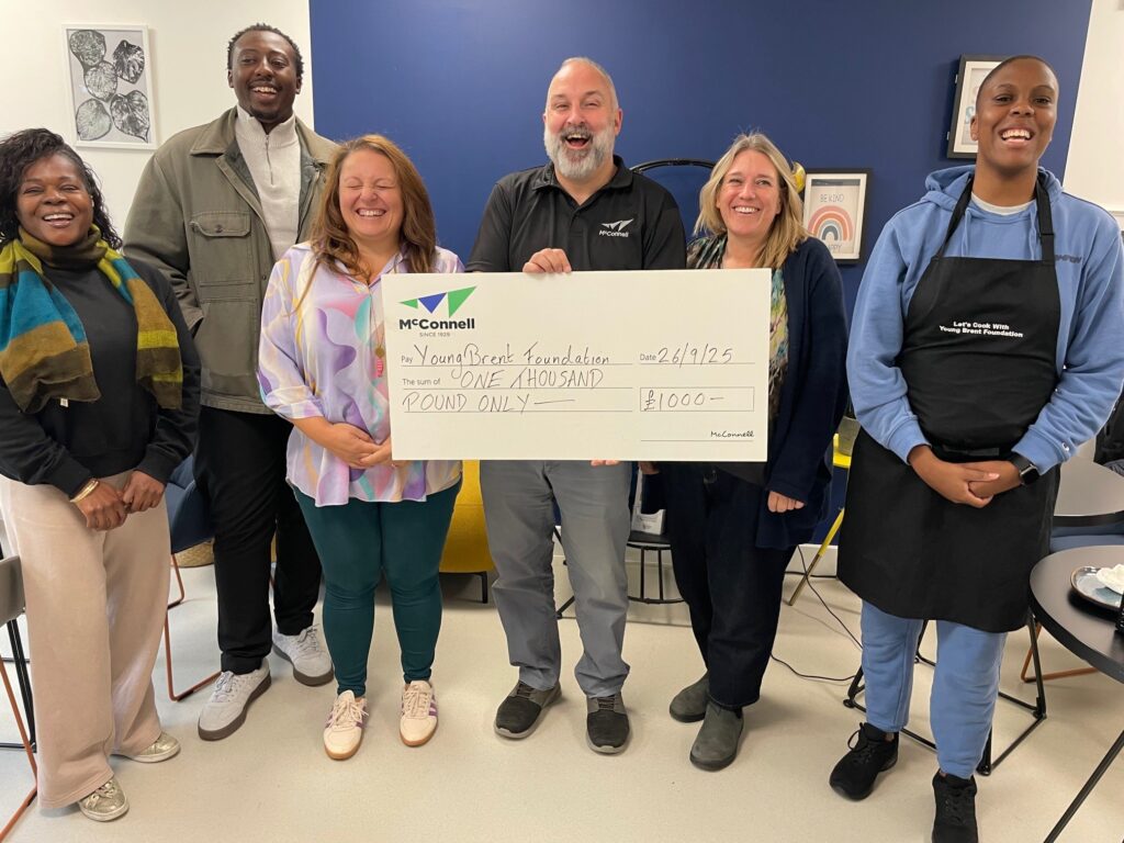 Julian Sanz stand with the Young Brent Foundation with a £1000 cheque.