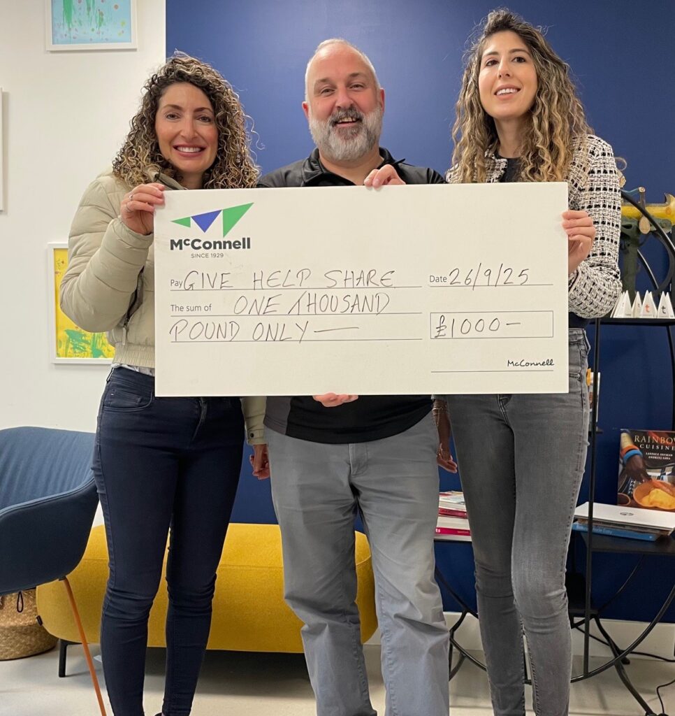 Julian Sanz stands with Amanda and Jacqueline from Give. Help. Share with a £1000 cheque.