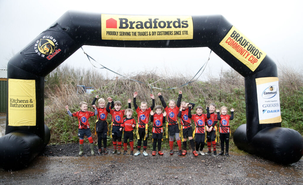 Young rugby players celebrate under the Bradfords Community Cup arch — an event run by Bradfords Building Supplies in partnership with Exeter Chiefs to promote wellbeing for young people.