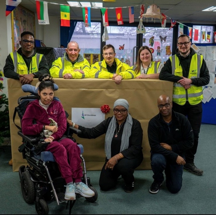 McConnell tradespeople gather beside a new large TV donated to the Brent Play Association to give young people and children with mobility issues better access to entertainment.