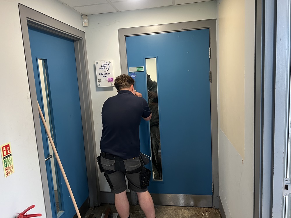 An employee of Alphatrack, April 2026's supplier of the month, is pictured reinstalling the fire doors at Jason Roberts Foundation